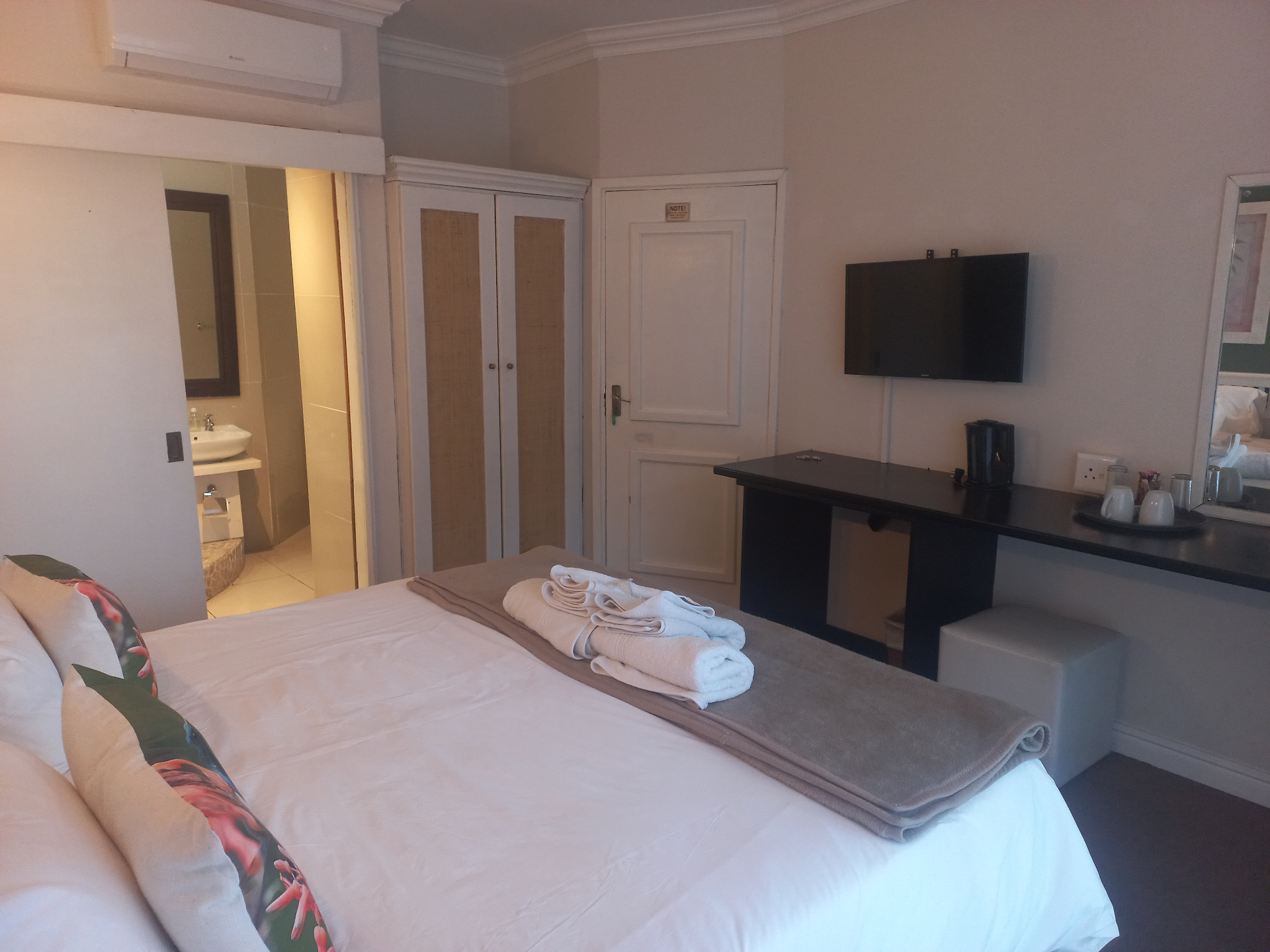 Raphia room showing the TV, desk area, and bathroom entrance.